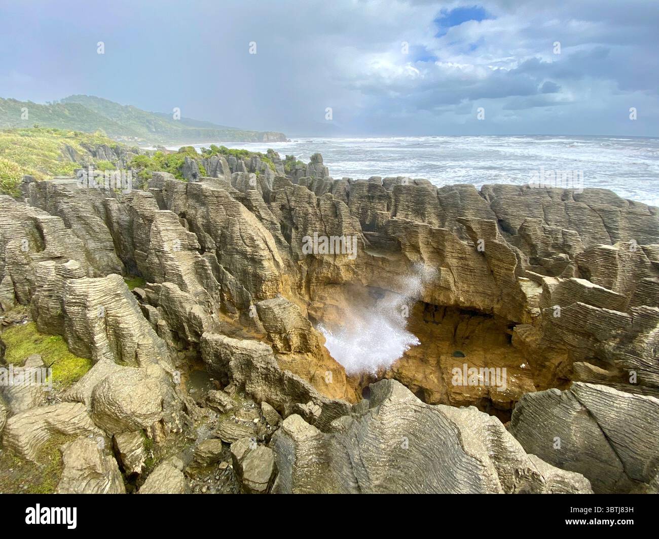 Un potente spray oceanico erutta da un traboccante tra i Pancake Rocks di pietra calcarea a strati sulla selvaggia costa occidentale della nuova Zelanda. Foto Stock