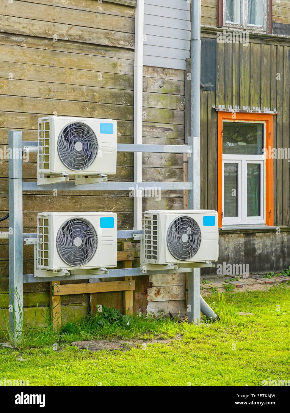Moderni sistemi a pompa di calore aria-aria installati all'esterno di una casa in legno intemprata, che presentano soluzioni di controllo climatico sostenibili Foto Stock