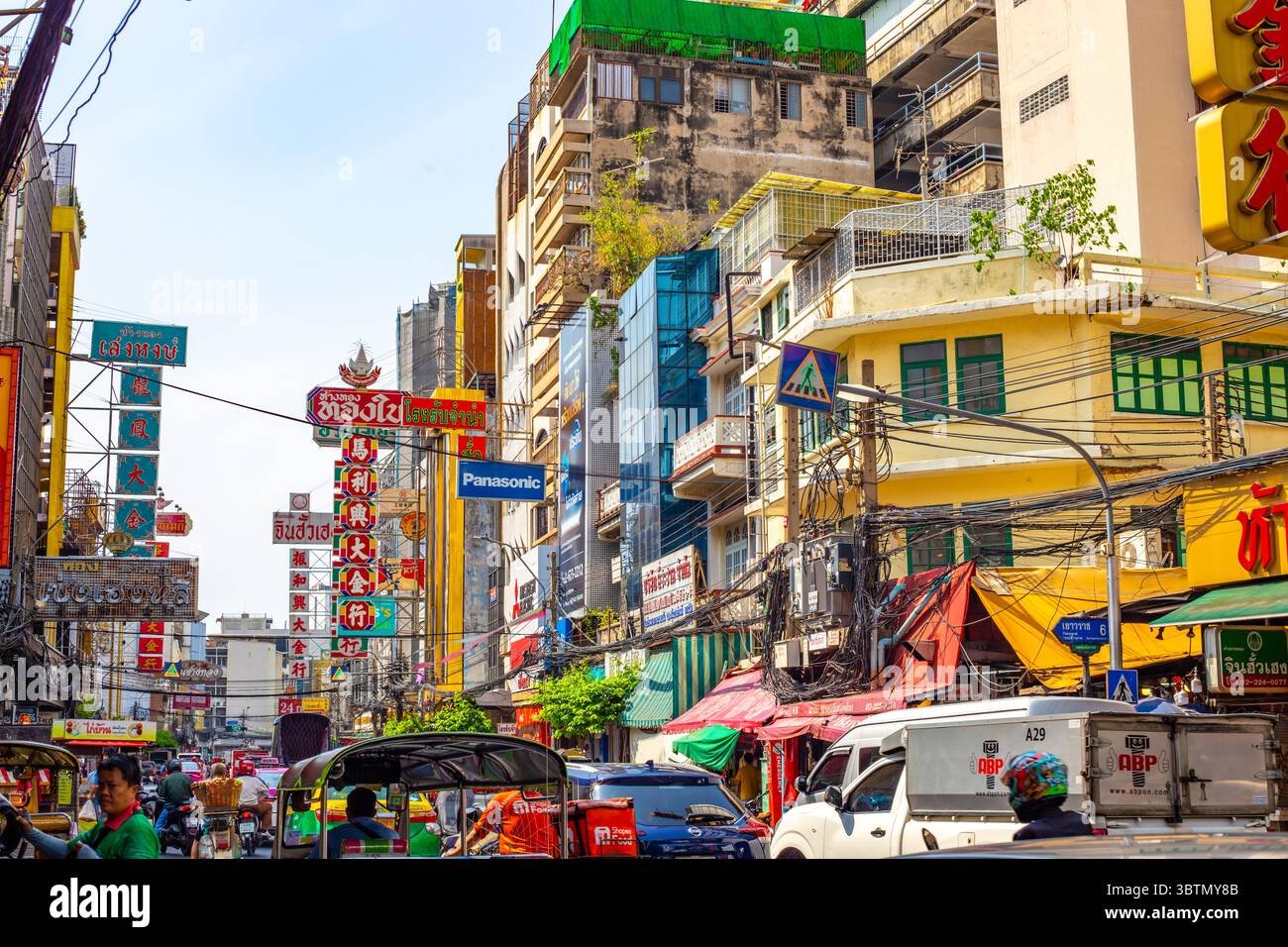Vista panoramica della trafficata strada di Bangkok con edifici colorati, cartelli, trasporti e tuk tuk che mostrano la vibrante energia della città. Thailandia, Ba Foto Stock