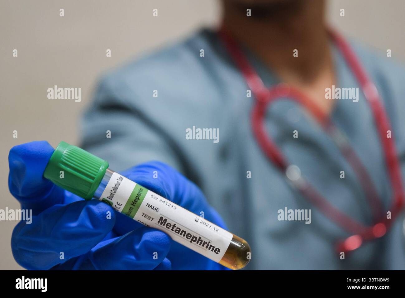 Testo metanefrina di è scritto su un campione di bottiglia con sfondo di un medico con una maschera di guanti medica. Concetto medico Foto Stock