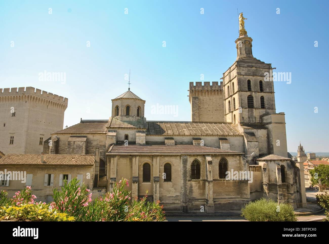 Storica cattedrale romanica con un campanile e una statua dorata in cima, situata in un complesso fortificato sotto il cielo azzurro. Foto Stock Storica cattedrale romanica con un campanile e una statua dorata in cima, situata in un complesso fortificato sotto il cielo azzurro. Foto Stock