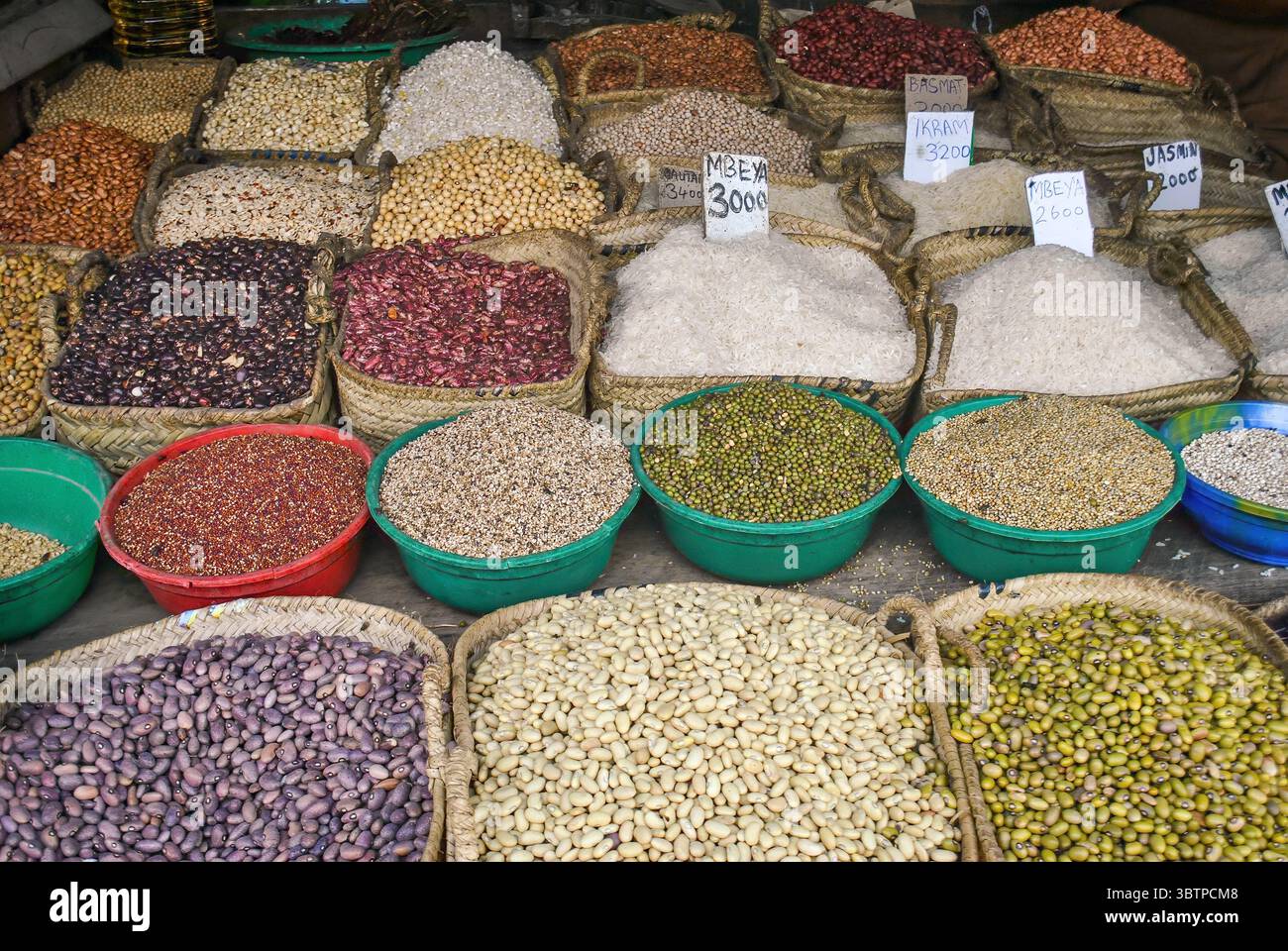 Varietà di cereali, fagioli e riso esposti in cesti e ciotole di plastica in un mercato all'aperto. Foto Stock