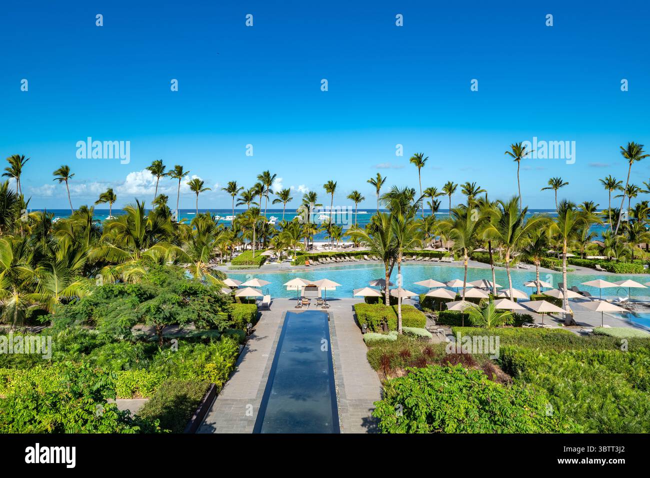 Bavaro Beach, Punta Cana: Una lussuosa area piscina del resort si fonde perfettamente con la splendida spiaggia caraibica e le palme. Foto Stock