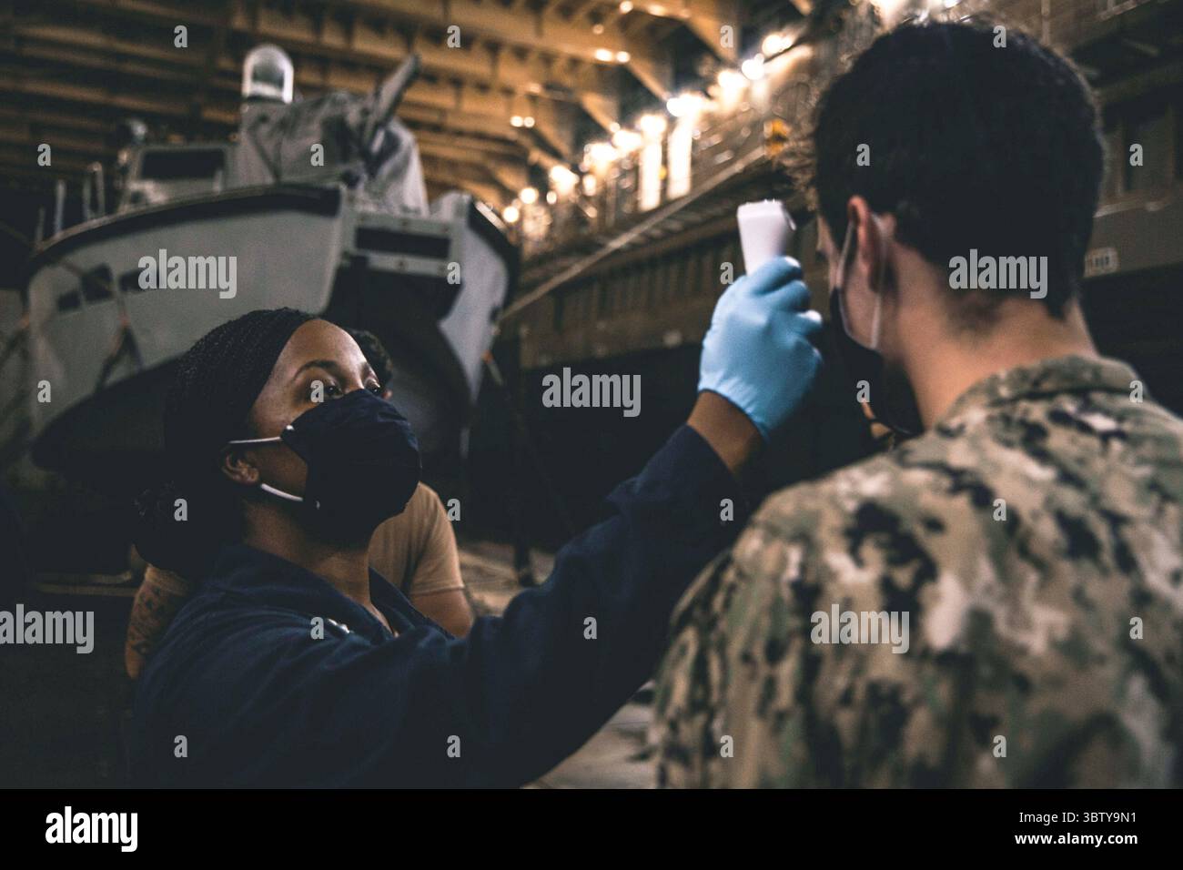 6 ottobre 2020 - U.S. 7th Fleet area of Responsibility - Un corpsman ospedaliero assegnato alla nave da sbarco anfibia USS Comstock (LSD 45) conduce procedure di mitigazione della COVID-19 sui marinai provenienti da pattugliatori (PB) Mk vi assegnato al comandante, Task Force 75 (CTF 75). Marine Expeditionary Security Force e Explosive Ordnance Disposal Mobile Unit Sailors assegnati al comandante, Task Force 75 (CTF 75) sono imbarcati e stanno conducendo operazioni di sicurezza marittima litorale integrate dalla nave da sbarco anfibia USS Comstock (LSD 45) con i Marines e i marinai già schierati come Task Force Foto Stock