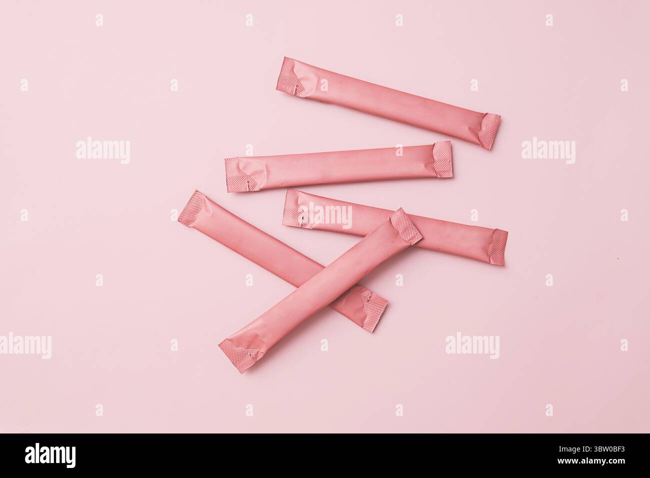 Sacchetti rosa, confezioni di bastoncini con spazio di copia su sfondo rosa coordinato. Estetica pulita per il branding. Foto Stock