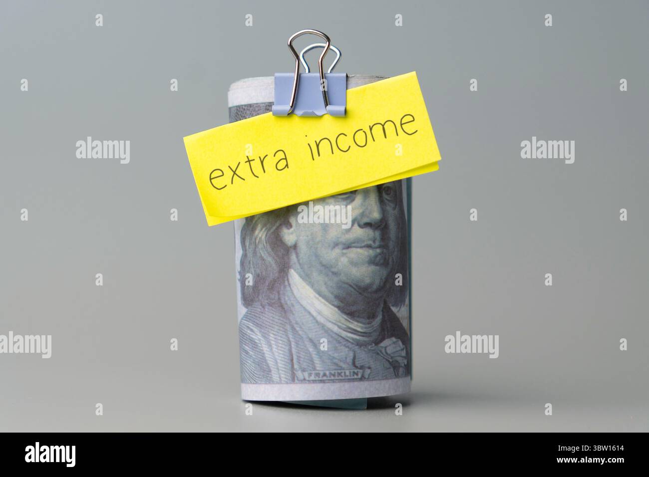 Una banconota da cento dollari con una nota "reddito extra". Concetto finanziario. Foto Stock
