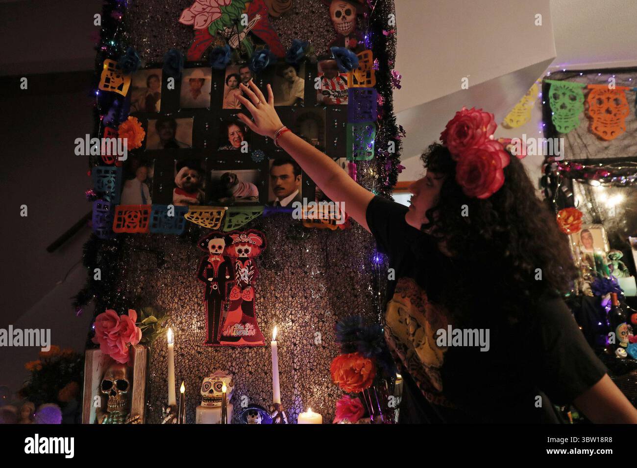 28 ottobre 2020, USA: Camila del Carmen De la o, 16 anni, punta alle fotografie dei parenti disposte su un elaborato ofrenda il 23 ottobre 2020, a Chicago. Camila e sua madre, Rosa Lilia De la o, decorano la loro casa per ricordare parenti e amici che sono morti. (Immagine di credito: © TNS via cavo ZUMA) Foto Stock