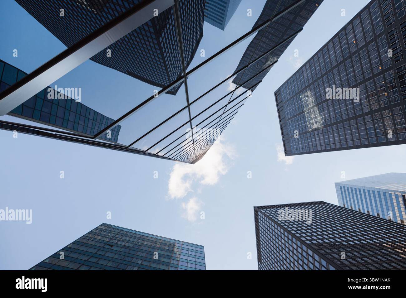 Torri di vetro per ufficio che formano il canyon a livello della strada, riflettendo la luce del sole sulle strutture a griglia Foto Stock