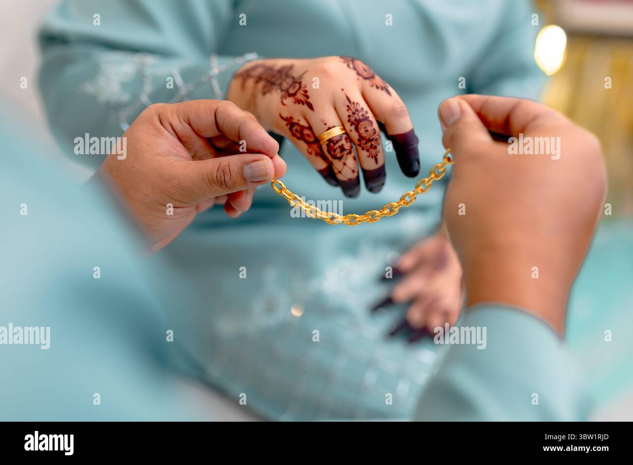 Uno sposo presenta una splendida catena d'oro alla sua sposa, un simbolo tradizionale di impegno e di amore duraturo nelle usanze matrimoniali malesi. Foto Stock