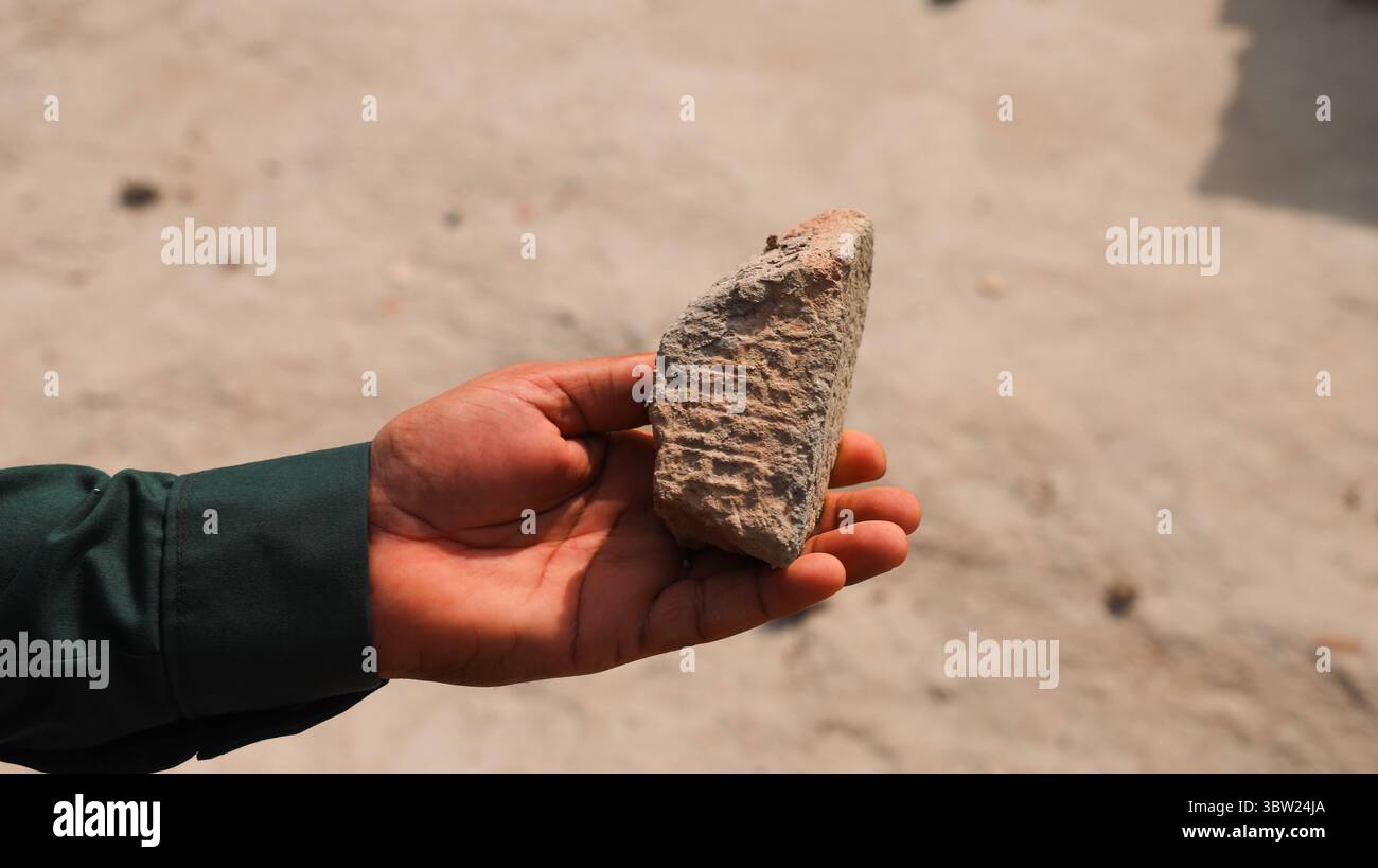 Una mano tiene in mano un manufatto in pietra intemprata rinvenuto a Uruk Iraq, che lascia intendere il ricco patrimonio storico e culturale delle regioni. Foto Stock