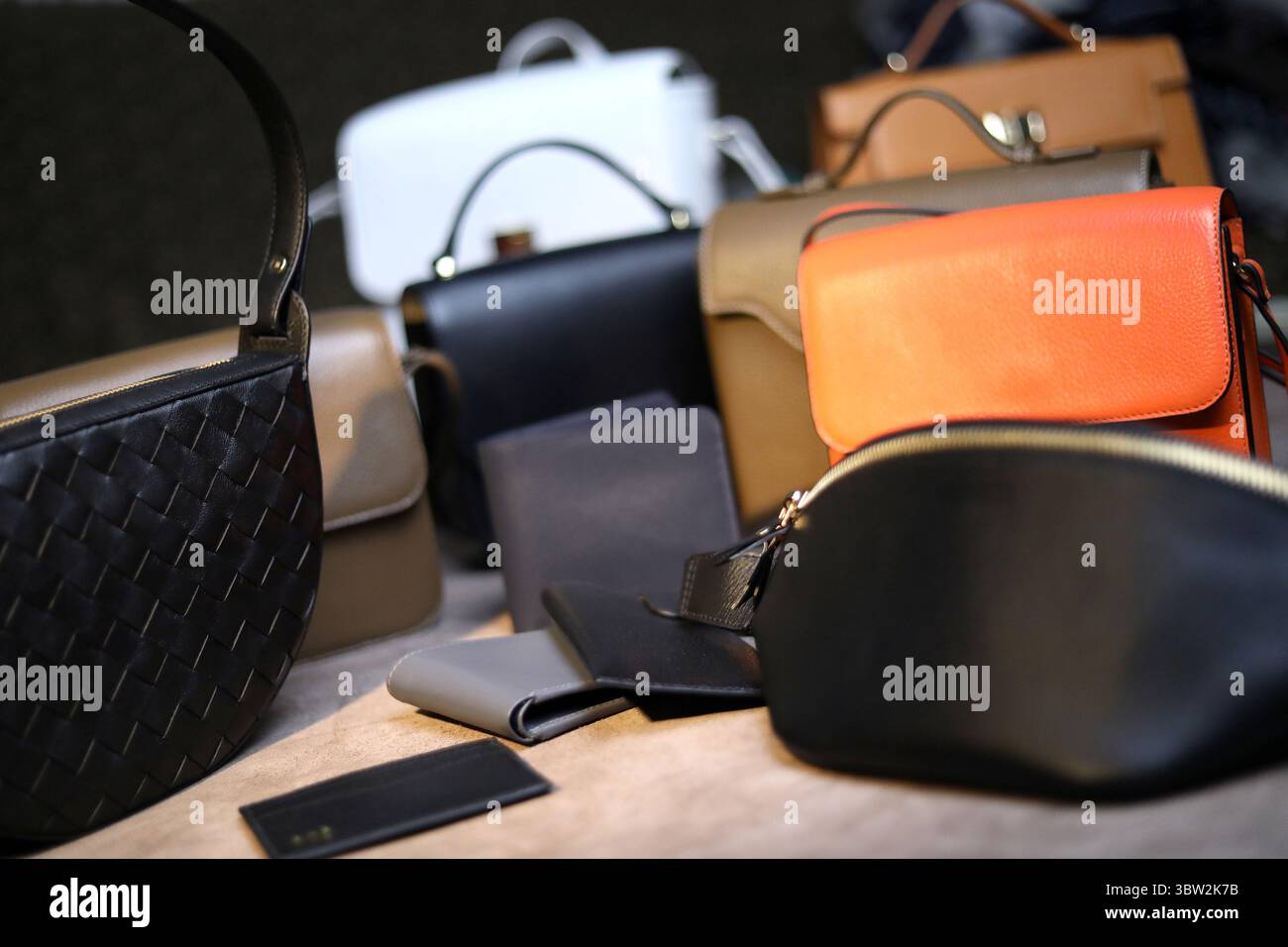 Un lussuoso assortimento di borse e portafogli firmati in vari stili e tonalità neutre, con un accessorio arancione che aggiunge un tocco di colore alla AM Foto Stock