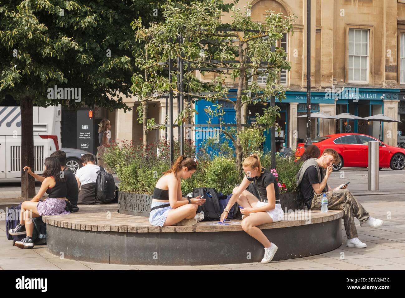 Inghilterra, Somerset, Bath, Dorchester Street, Street Scene, persone che si rilassano sotto gli alberi Foto Stock