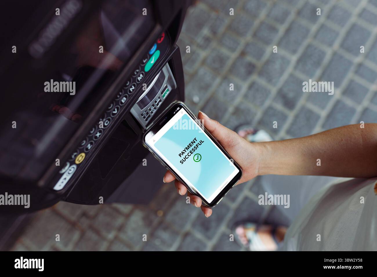 Donna che paga il biglietto del parcheggio tramite telefono. Pagamenti elettronici. Tecnologia NFC. Pagamenti mobili veloci. Comodità e sicurezza Foto Stock