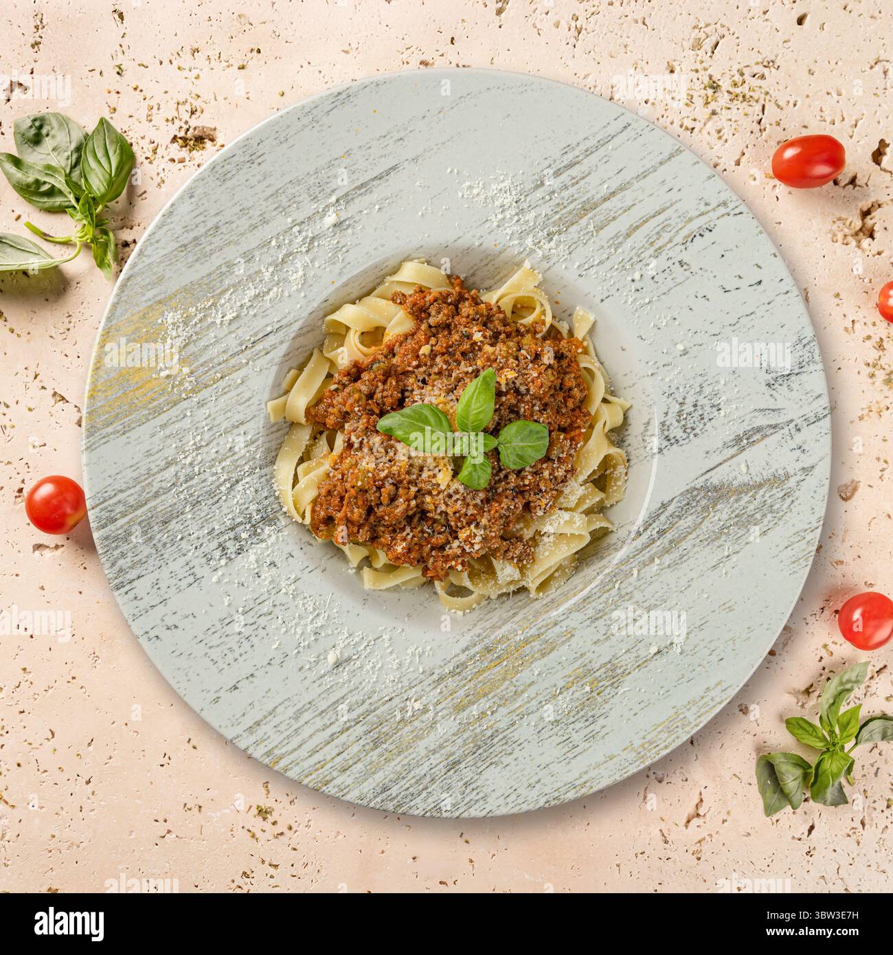 Gustose tagliatelle con salsa alla bolognese, parmigiano e foglie di basilico, creando una perfetta scena culinaria Foto Stock