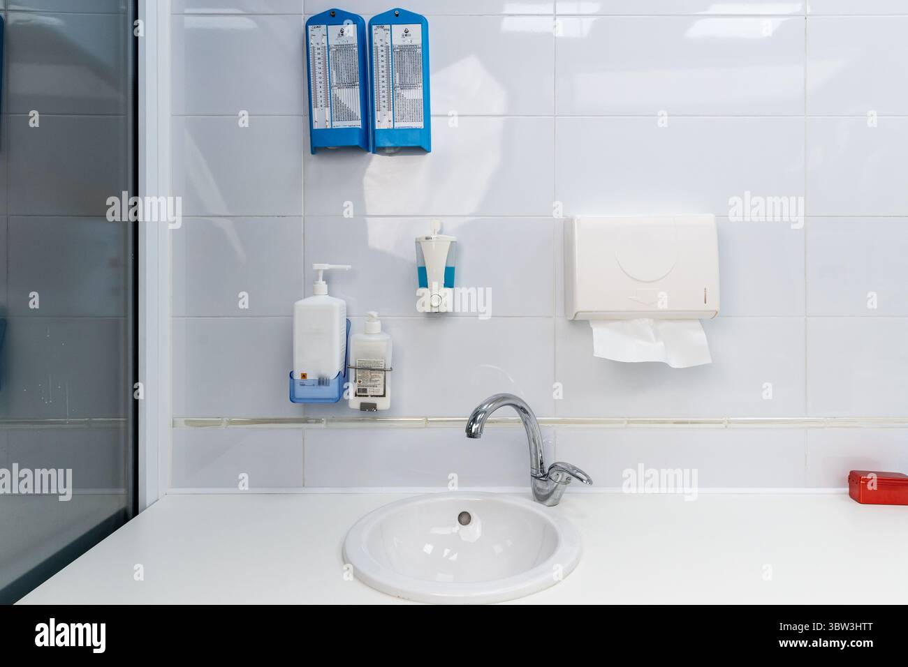 Moderno bagno con igienizzatore per le mani e dispenser di asciugamani di carta in un ambiente di colore chiaro con servizi di base per una migliore igiene e. Foto Stock