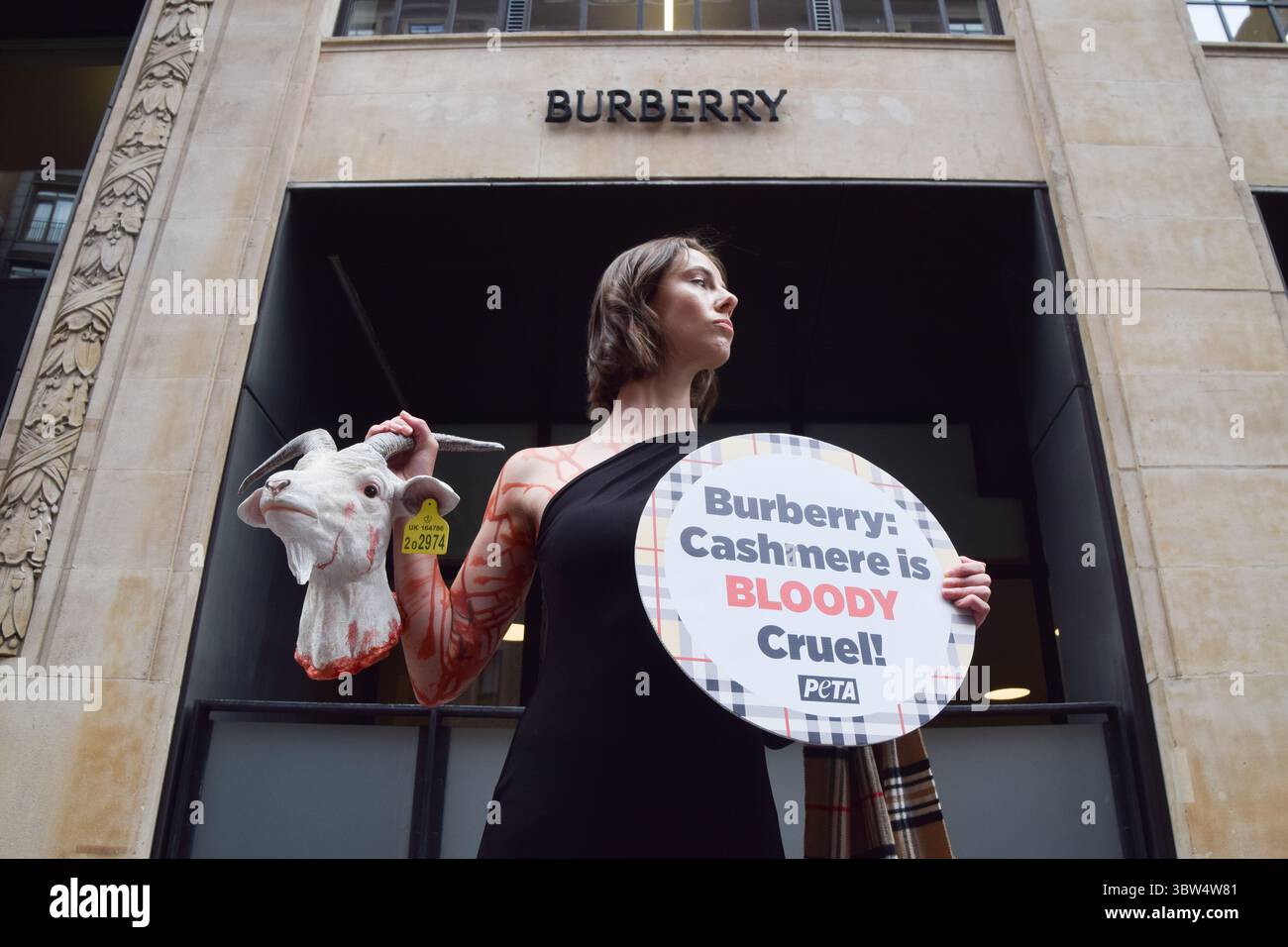 Londra, Regno Unito. 16 luglio 2025. Un attivista della PETA si erge con una "testa di capra recisa" artificiale e un cartello che dice "il cashmere è crudele" fuori dalla sede di Burberry a Horseferry House mentre il gruppo della moda tiene la sua Assemblea generale annuale (AGM). L'azione fa parte della campagna in corso del gruppo per i diritti degli animali che chiede a Burberry di eliminare il cashmere dai suoi prodotti e di utilizzare invece tessuti vegani. Crediti: Vuk Valcic/Alamy Live News Foto Stock