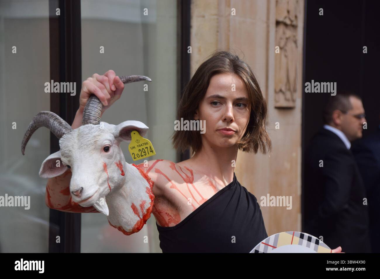 Londra, Regno Unito. 16 luglio 2025. Un attivista della PETA si erge con una "testa di capra recisa" artificiale e un cartello che dice "il cashmere è crudele" fuori dalla sede di Burberry a Horseferry House mentre il gruppo della moda tiene la sua Assemblea generale annuale (AGM). L'azione fa parte della campagna in corso del gruppo per i diritti degli animali che chiede a Burberry di eliminare il cashmere dai suoi prodotti e di utilizzare invece tessuti vegani. Crediti: Vuk Valcic/Alamy Live News Foto Stock