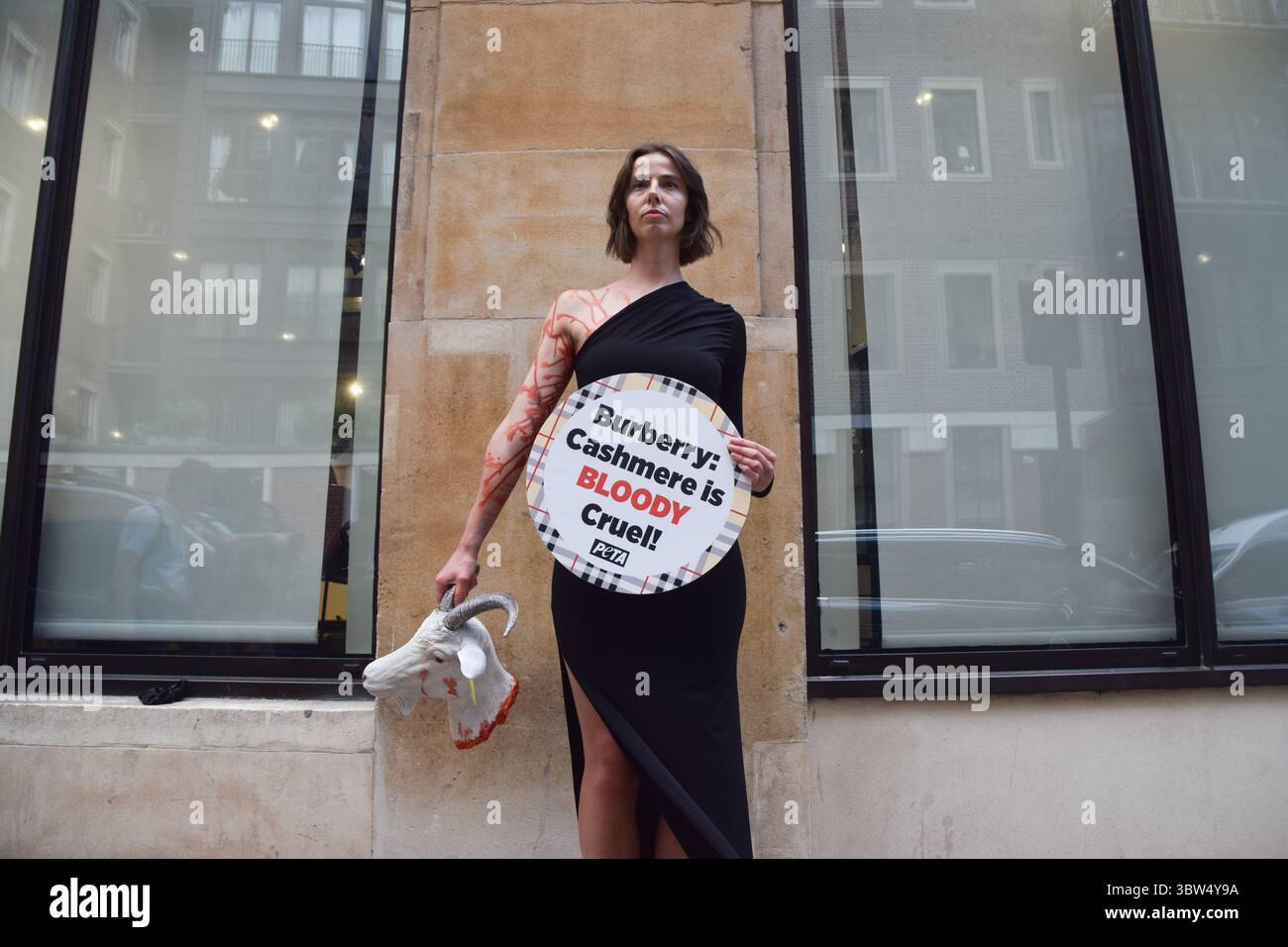 Londra, Regno Unito. 16 luglio 2025. Un attivista della PETA si erge con una "testa di capra recisa" artificiale e un cartello che dice "il cashmere è crudele" fuori dalla sede di Burberry a Horseferry House mentre il gruppo della moda tiene la sua Assemblea generale annuale (AGM). L'azione fa parte della campagna in corso del gruppo per i diritti degli animali che chiede a Burberry di eliminare il cashmere dai suoi prodotti e di utilizzare invece tessuti vegani. Crediti: Vuk Valcic/Alamy Live News Foto Stock
