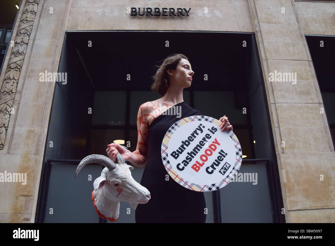Londra, Regno Unito. 16 luglio 2025. Un attivista della PETA si erge con una "testa di capra recisa" artificiale e un cartello che dice "il cashmere è crudele" fuori dalla sede di Burberry a Horseferry House mentre il gruppo della moda tiene la sua Assemblea generale annuale (AGM). L'azione fa parte della campagna in corso del gruppo per i diritti degli animali che chiede a Burberry di eliminare il cashmere dai suoi prodotti e di utilizzare invece tessuti vegani. Crediti: Vuk Valcic/Alamy Live News Foto Stock