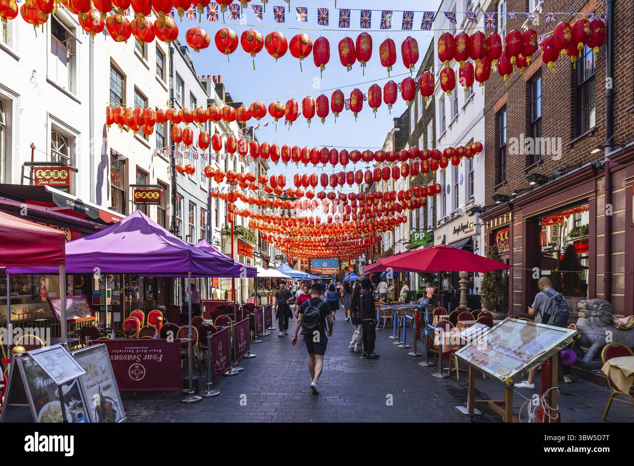 Questa foto cattura la vivace scena di London China Town, mostrando lanterne decorative e vivaci strade fiancheggiate da negozi e ristoranti Foto Stock
