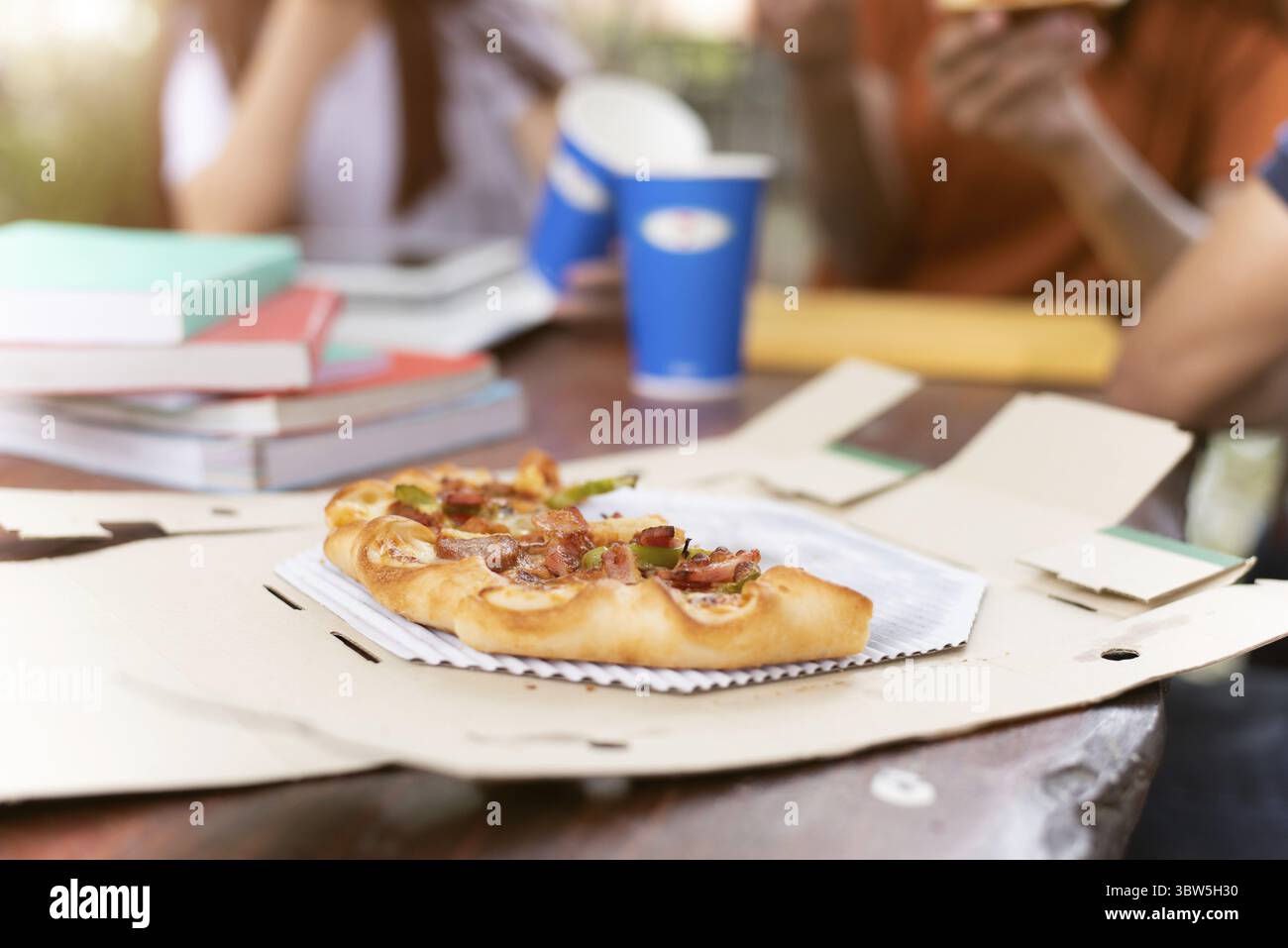 La Pizza in scatola di mandata con persone amicizie parte dello sfondo. Fette di Pizza di pezzi sul tavolo per esterno celebrare in aula da studente di college dopo esame Foto Stock