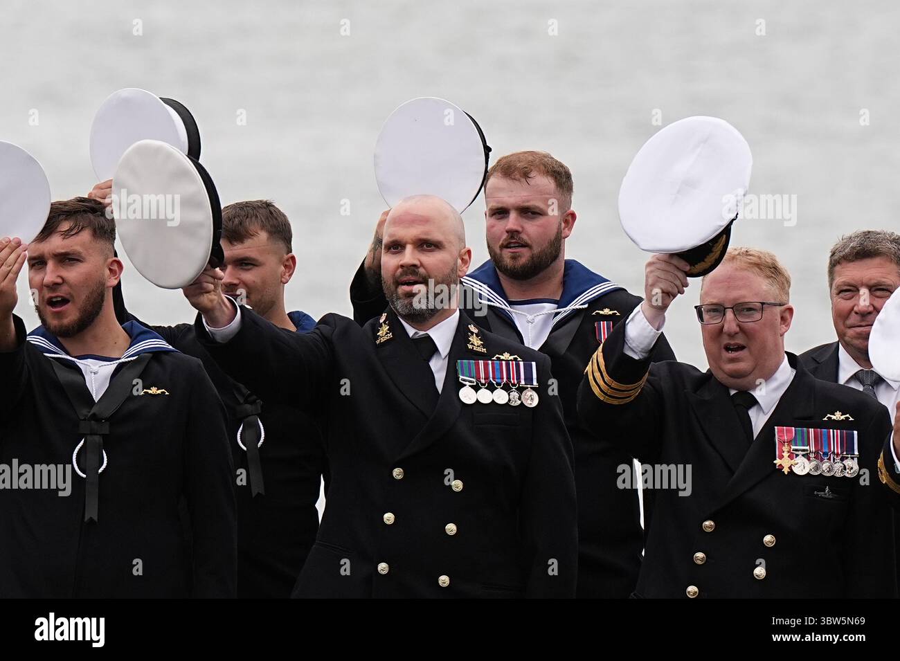 La compagnia della nave regala una tradizionale "Cheer Ship" della Royal Navy per la regina Camilla, Lady Sponsor della HMS Astute, durante una visita alla HMNB Devonport a Plymouth, Devon, per segnare la fine della prima commissione del sottomarino, che è la prima commissione più lunga di qualsiasi sottomarino della Royal Navy nella storia, con oltre 15 anni. Data foto: Mercoledì 16 luglio 2025. Foto Stock