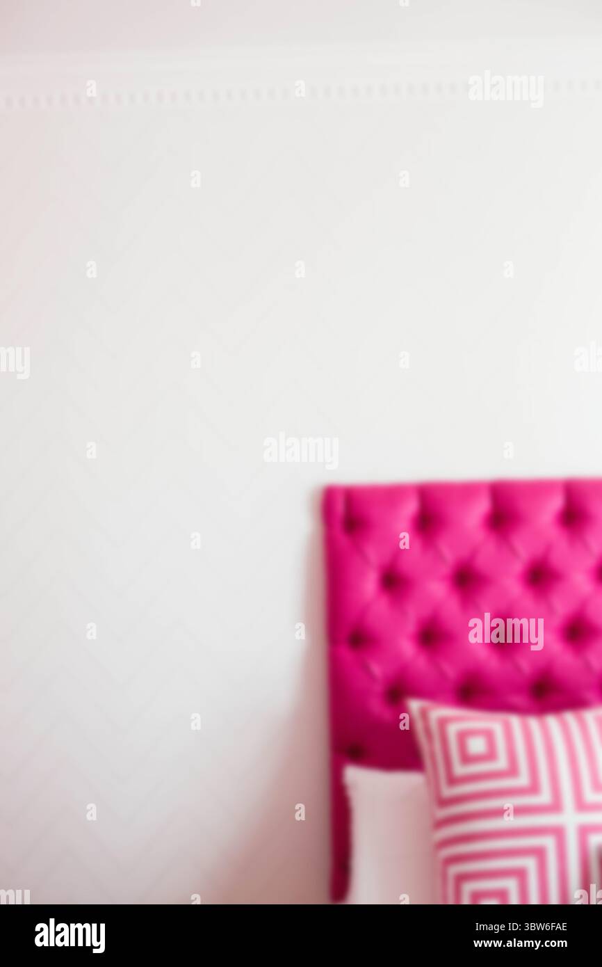 Cuscino su un letto rosa contro una parete bianca Foto Stock