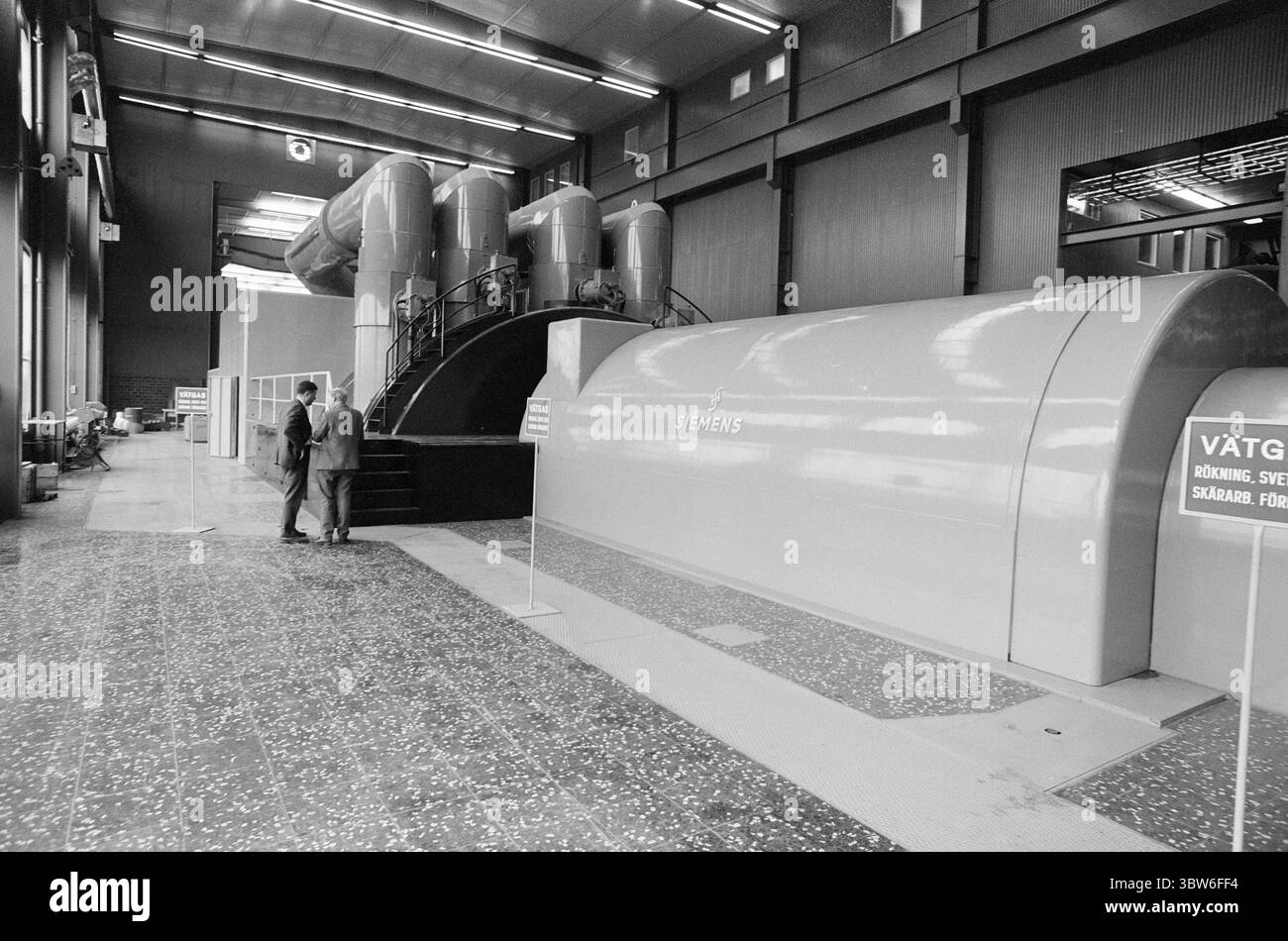 Corrente 42-4-1970 : la potenza petrolifera fornisce una città pulita. La costruzione di centrali elettriche non è sempre necessaria alla distruzione naturale e ai disturbi ambientali. A Västerås, in Svezia, il fabbisogno energetico e termico è stato coperto dalla costruzione di una centrale petrolifera collegata a una rete di teleriscaldamento. Il risultato: | oggi, Västerås può pubblicizzare con l'aria urbana più pulita della Svezia. Tutto il riscaldamento residenziale inquinante dell'aria con petrolio, carbone e legno è praticamente sparito. E il teleriscaldamento mantiene la neve e il ghiaccio fuori dalle strade. Nella sala turbine dell'impianto di cogenerazione. Qui ci sono dimensioni molto grandi e una Foto Stock