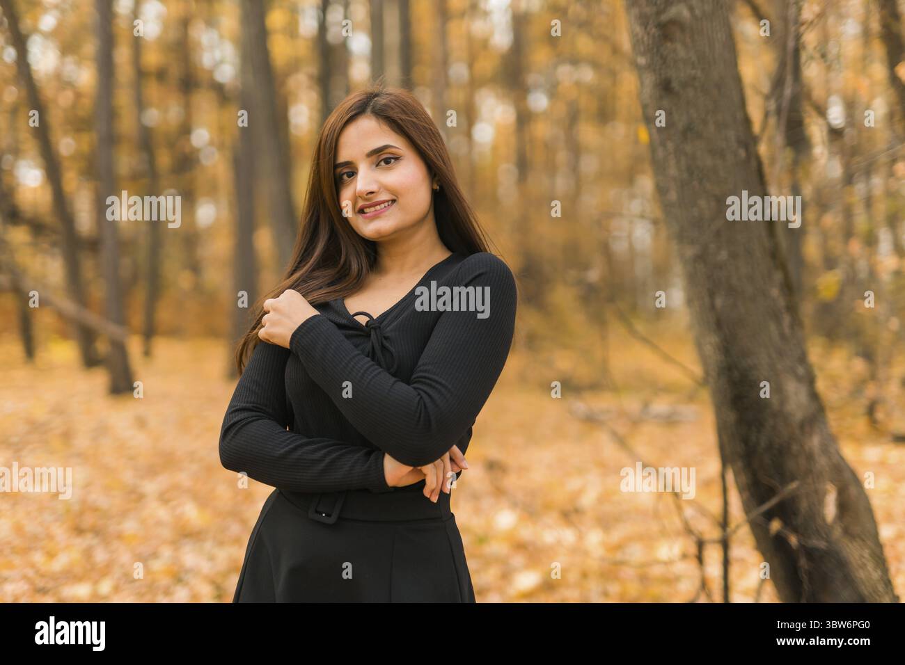 Ritratto ravvicinato della diversità giovane bella donna indiana asiatica con un abito nero in copia all'aperto autunnale. Sorriso felice e naturale Foto Stock