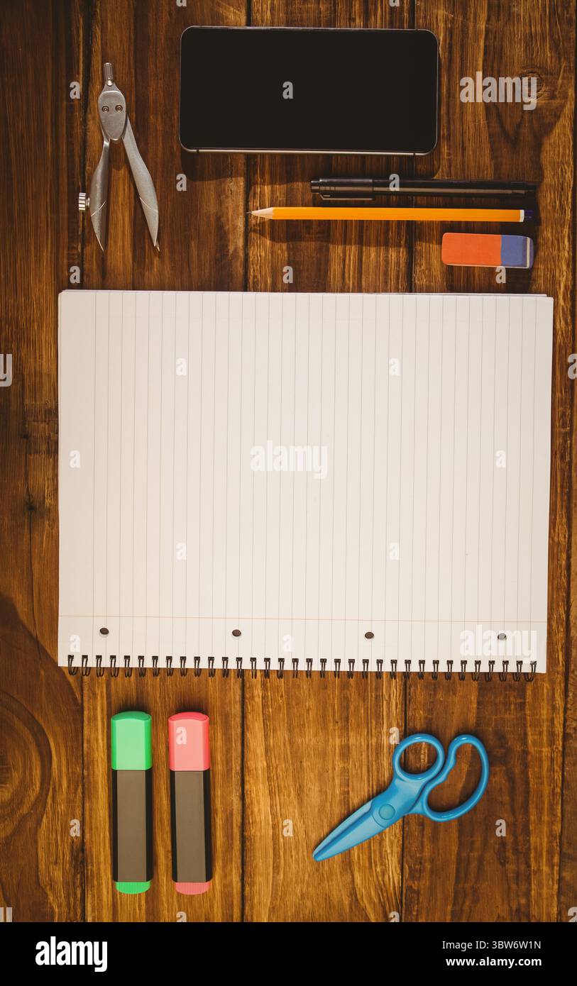 Il notebook aperto a spirale si trova su una scrivania in legno dal design piatto con smartphone e cancelleria Foto Stock