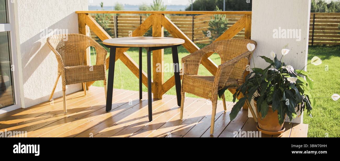 Banner accogliente terrazza in legno di casa di campagna o cottage con vista giardino - tavolo e sedia per una serata rilassante. Foto Stock