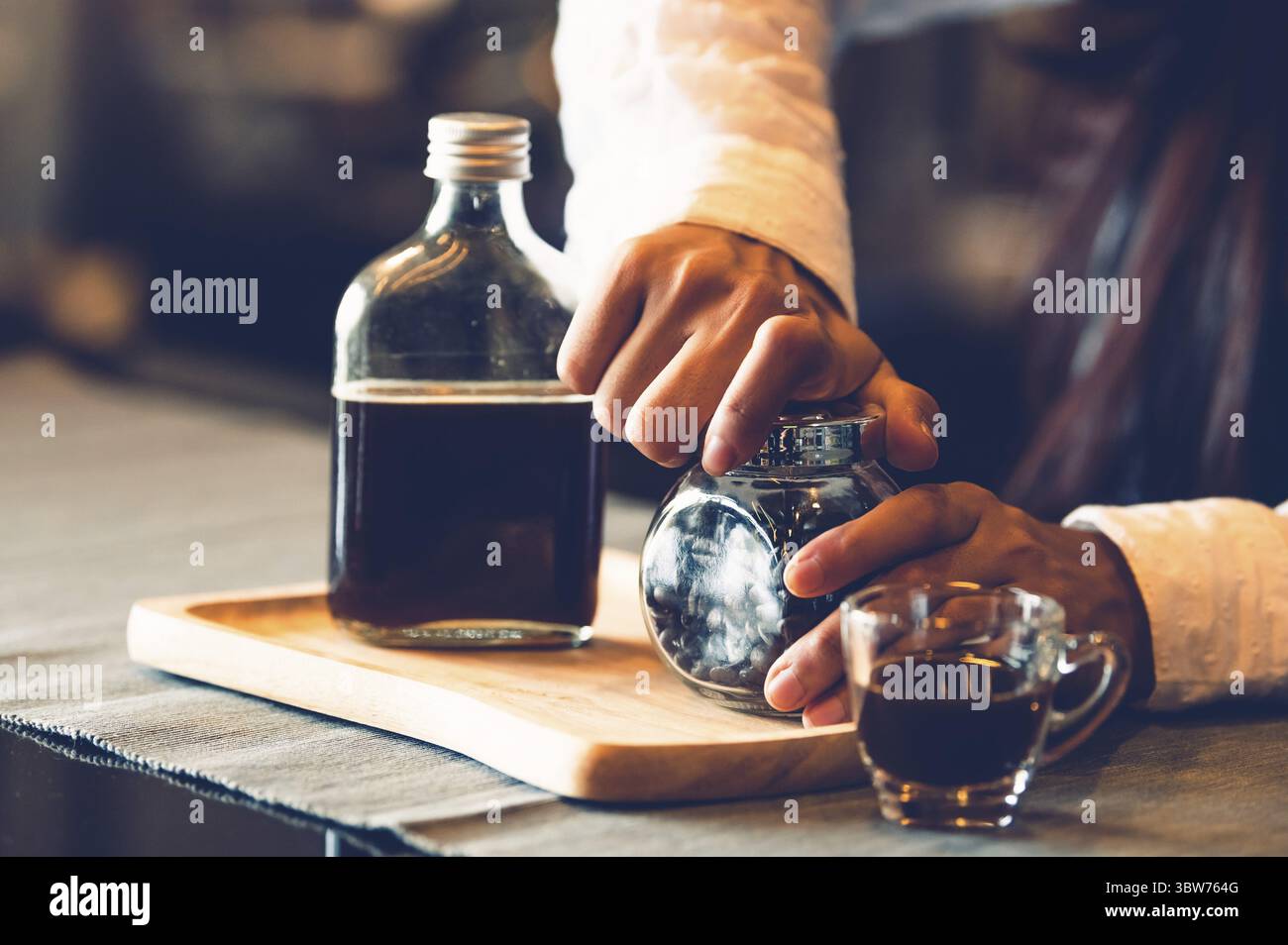 Primo piano della femmina professionale barista lato apertura del flacone di caffè per rendere tazza di caffè. Felice giovane donna al bancone bar nel ristorante backgroun Foto Stock