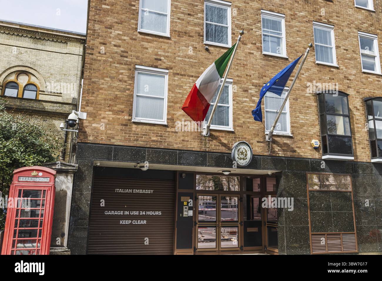 Edificio storico londinese che ospita l'Ambasciata Italiana con bandiere e cabina telefonica rossa. Londra, Regno Unito, 6 aprile 2024 Foto Stock
