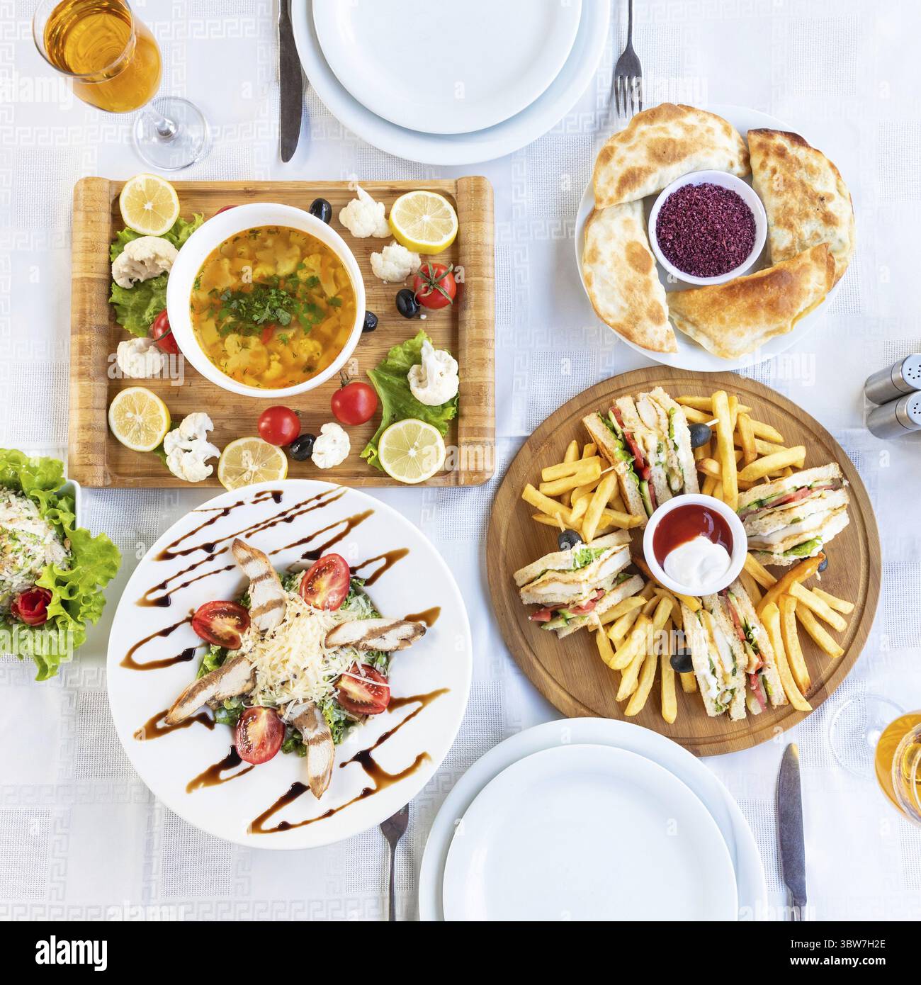 Club sandwich con patatine fritte e zuppa, insalata sul tavolo, vista dall'alto Foto Stock