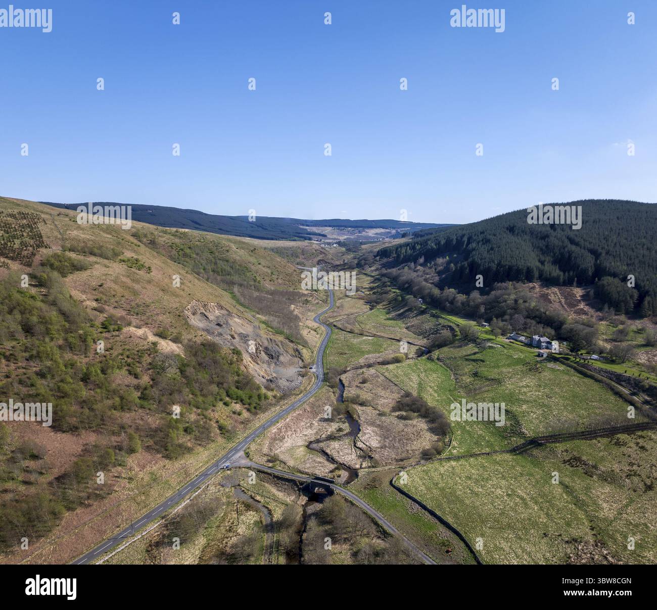 Veduta aerea di una strada tortuosa che serpeggia tra valli verdeggianti e aspre colline, immersa nel soffice bagliore della luce del giorno, Hawick, Scozia, Regno Unito. Foto Stock