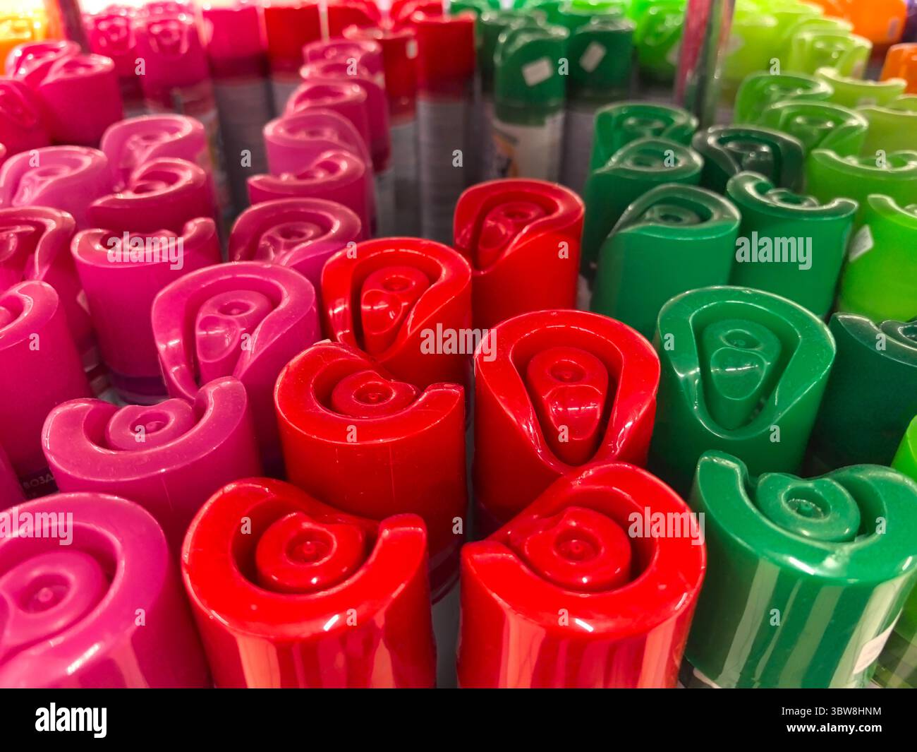 I cappellini dai colori vivaci nelle tonalità rosa, rosso e verde sono allineati in modo ordinato, a creare un'atmosfera giocosa in uno spazio di lavoro creativo. Ideale per gli artisti Foto Stock
