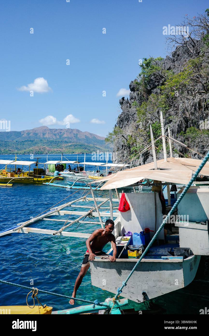 Un design unico di un tour in barca filippina a coda lunga con un pescatore asiatico che è una firma nelle isole Coron. Bell'oceano blu profondo Foto Stock