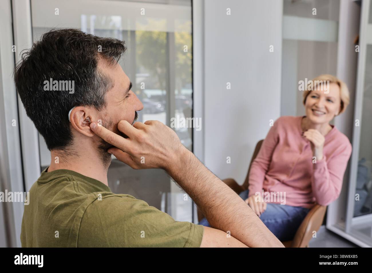 Due amici discutono dell'importanza del collegamento e della comprensione con un apparecchio acustico. Soluzioni per l'udito Foto Stock