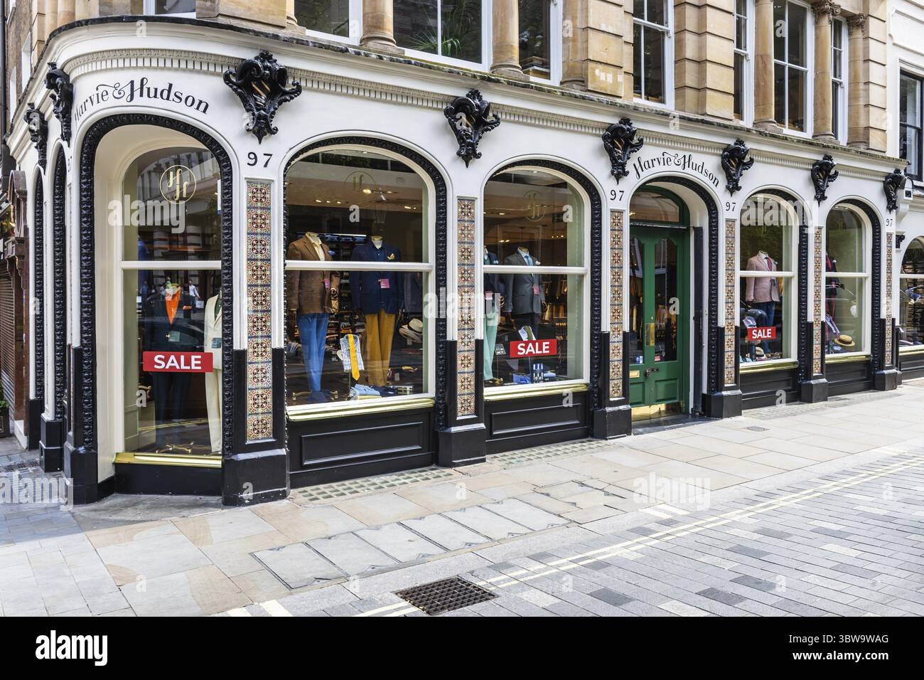 L'elegante boutique di Harvie and Hudson a Londra, con finestre ad arco, cartelli di vendita e design classico su una strada acciottolata Foto Stock