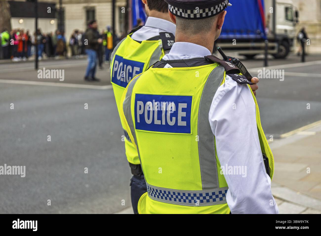 Agente di polizia in giubbotto ad alta visibilità in servizio in un'area urbana, garantendo la sicurezza e l'applicazione della legge Foto Stock