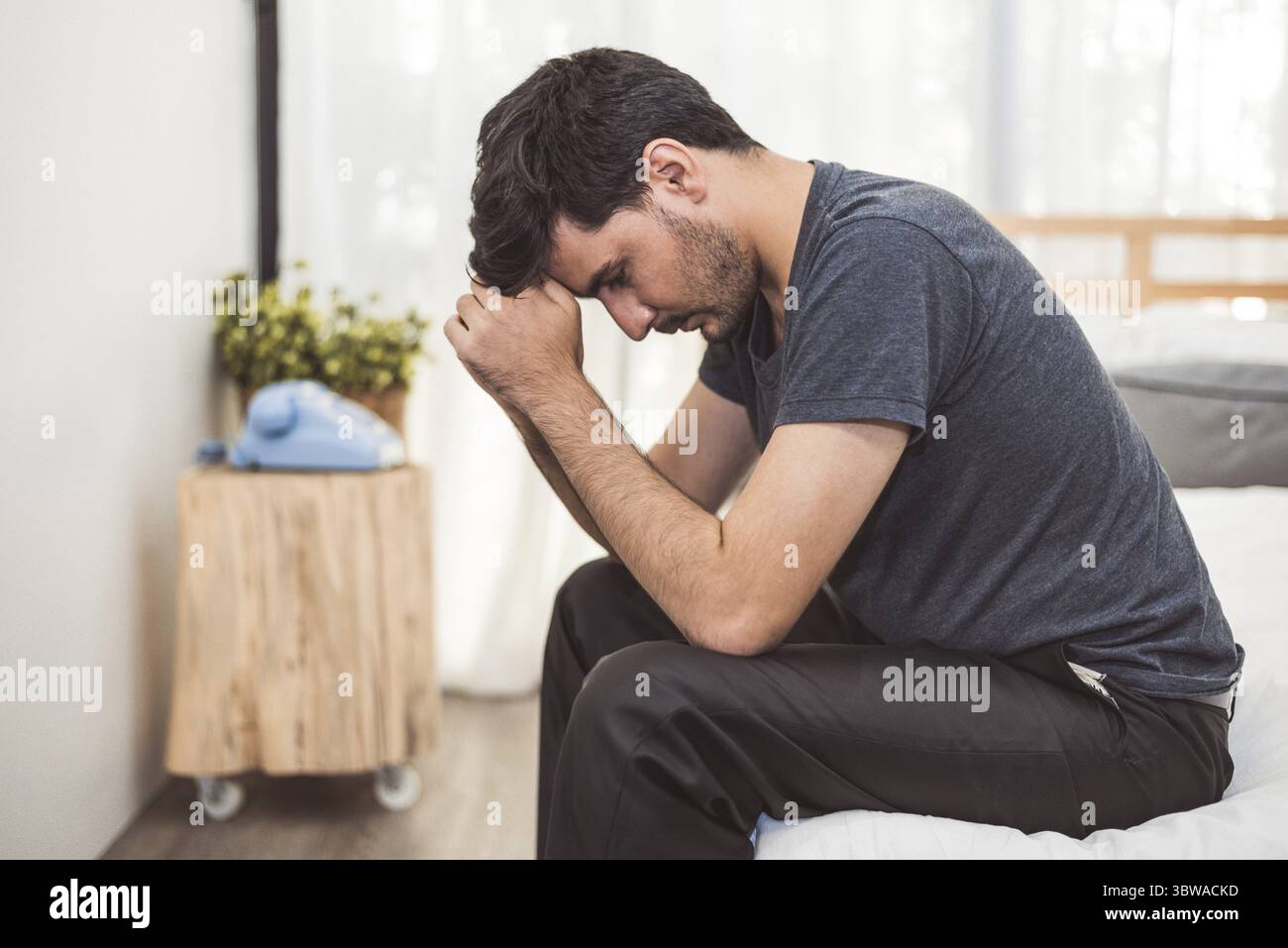 Preoccupato uomo seduto sul letto con la mano sulla fronte in camera da letto in grave stato d'animo le emozioni. Disturbo depressivo maggiore chiamato concetto MDD. Lonely sintomo di m Foto Stock