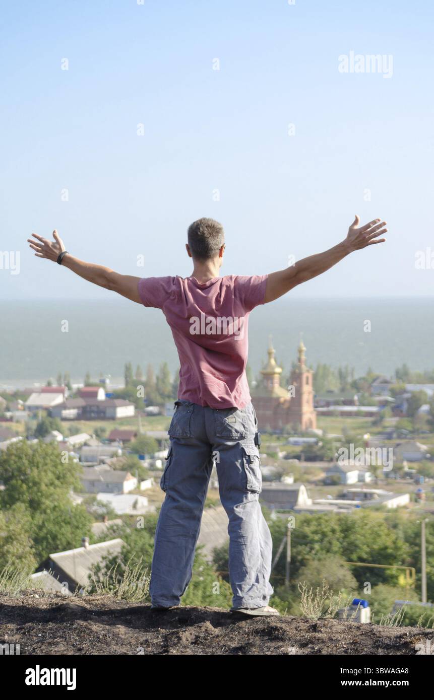 Il giovane atletico ha sparso le braccia sulla scogliera Foto Stock