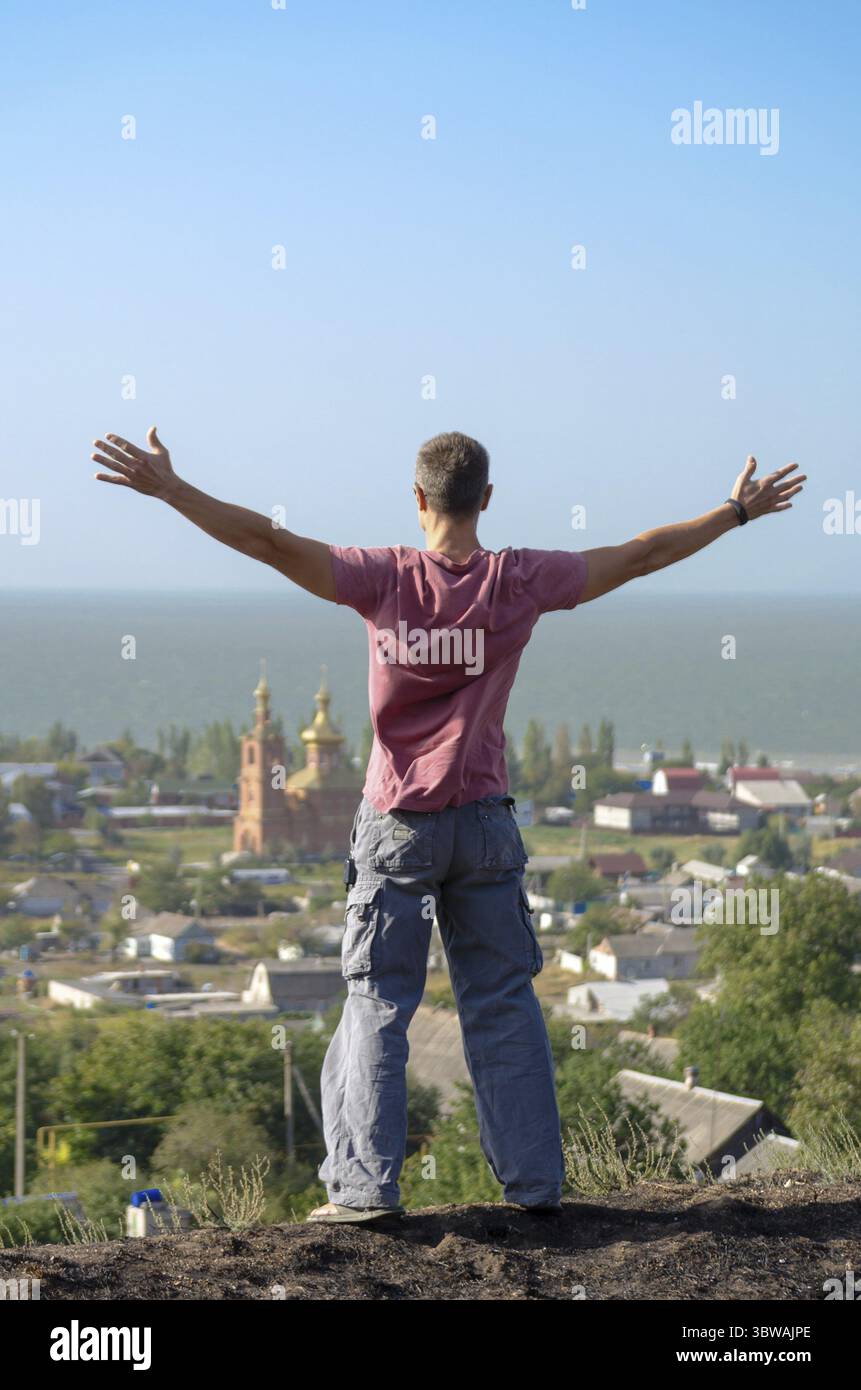 Il giovane atletico ha sparso le braccia sulla scogliera Foto Stock