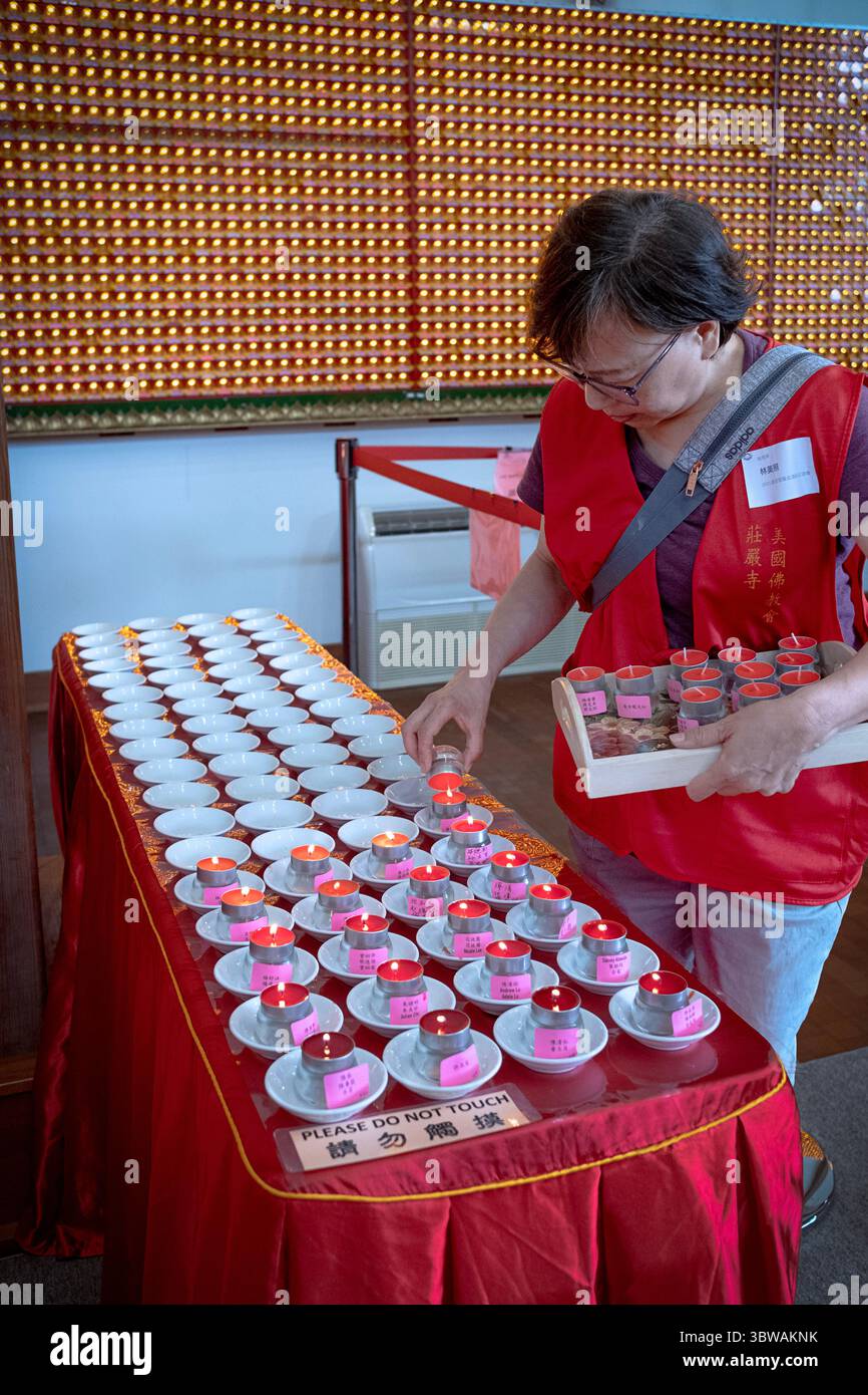 Un volontario del tempio accende piccole candele di tè dando inizio alla cerimonia illuministica di Kuan Yin Bodhisattva in un monastero di Carmel, Putnam County, NY. Foto Stock