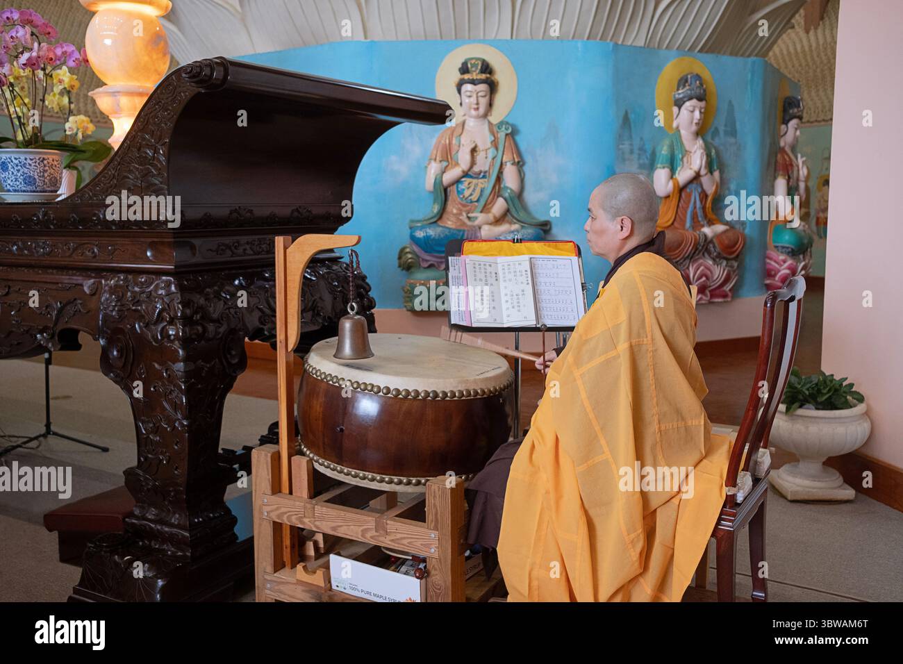 Una suora cinese-americana si tocca il tamburo metallico durante una cerimonia illuministica di Kuan Yin Bodhisattva nella sala del grande Buddha del monastero di Chuang Yen a New York. Foto Stock