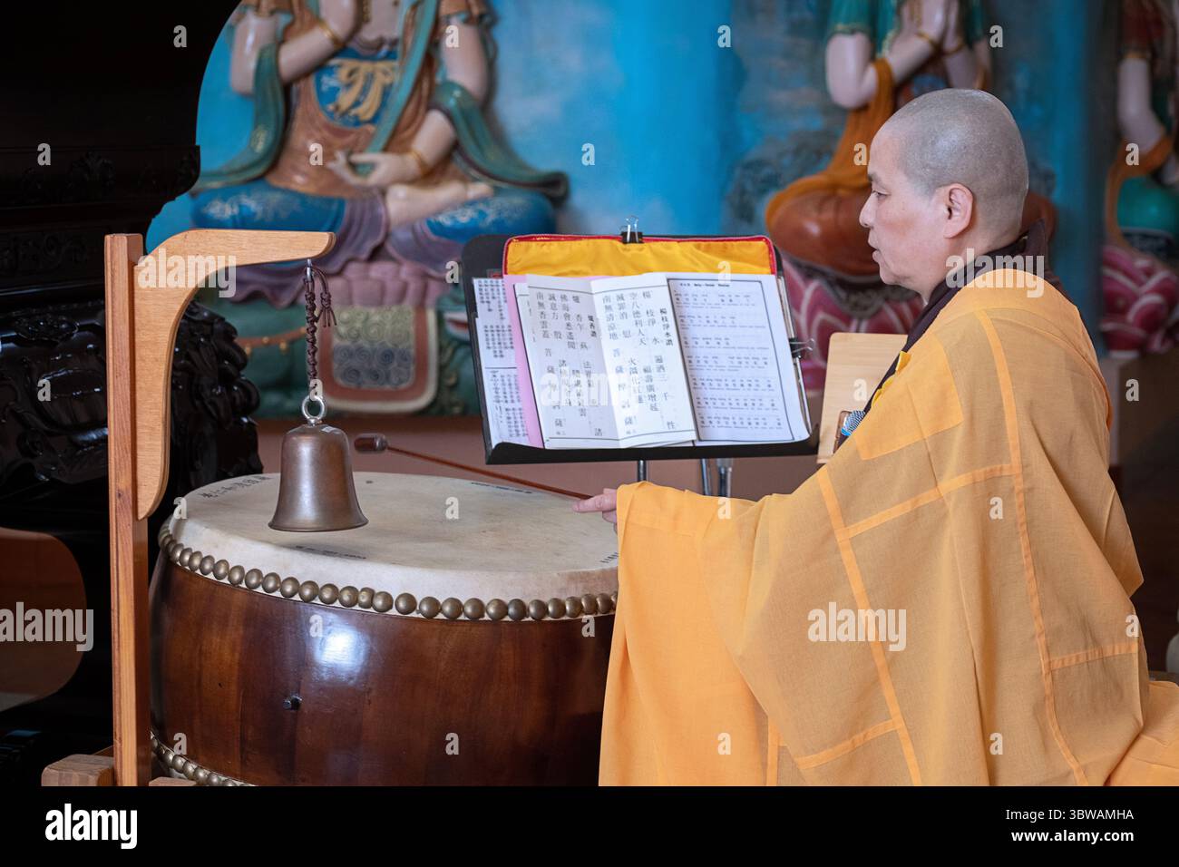 Una suora cinese-americana si tocca la sua batteria di metallo durante una cerimonia illuministica di Kuan Yin Bodhisattva in un monastero a Carmel, New York. Foto Stock