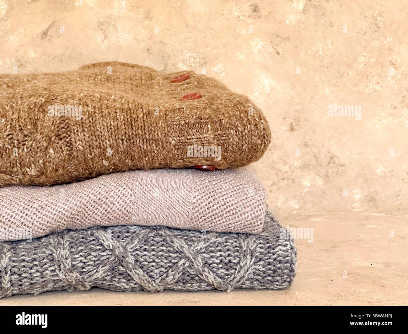 Una calda e invitante pila di maglioni in maglia in tonalità neutre, perfetti per mostrare l'essenza dell'autunno e del tempo Foto Stock