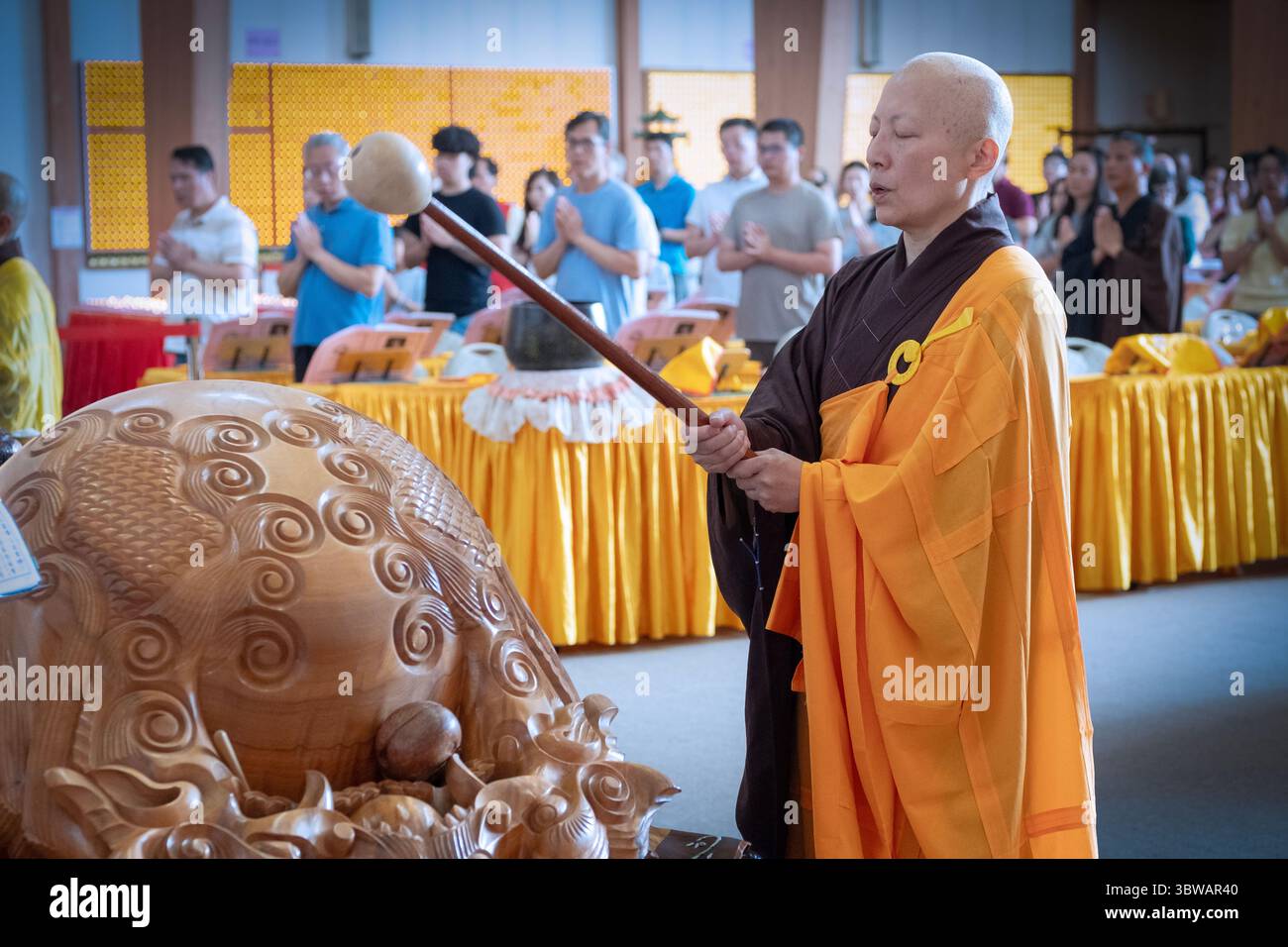 Una suora buddista suora suona il tamburo di legno mokugyo ad una cerimonia illuministica di Kuan Yin Bodhisattva in un monastero a Carmelo, New York. Foto Stock