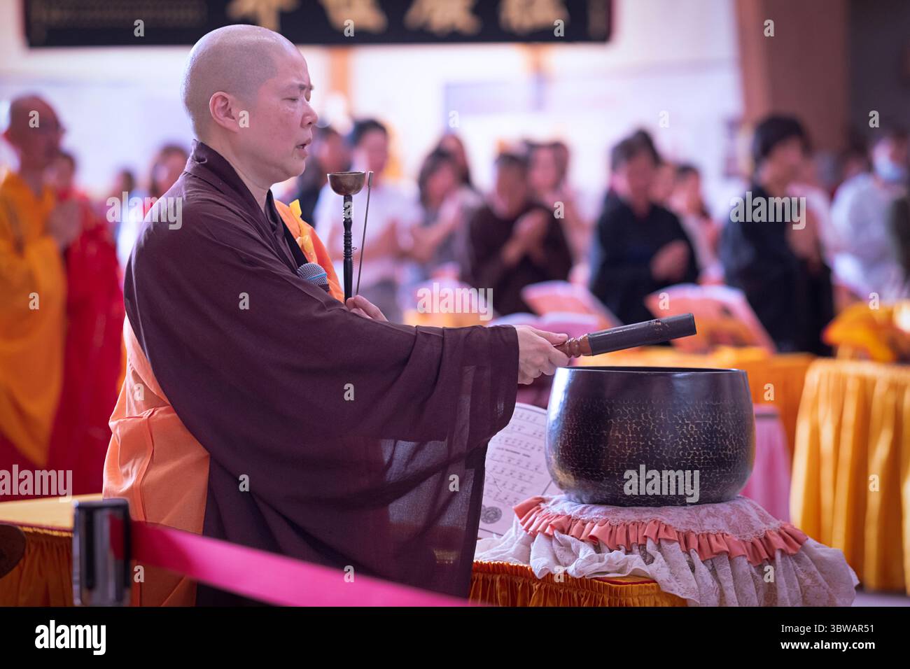 Una suora cinese-americana si tocca la sua batteria di metallo durante una cerimonia illuministica di Kuan Yin Bodhisattva in un monastero a Carmel, New York. Foto Stock