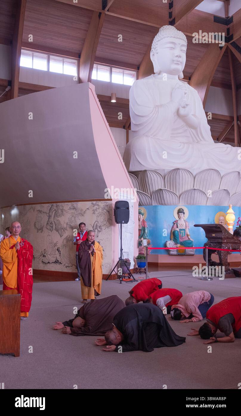 Un sacerdote abate buddista conduce la congregazione ad una cerimonia illuministica di Kuan Yin Bodhisattva nella sala del grande Buddha in un monastero del Carmelo. Foto Stock